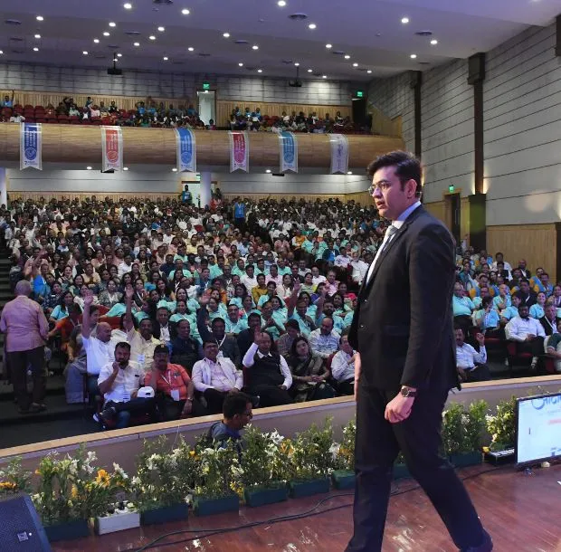 Sonu Sharma walking across the stage during an academic session in a decorated auditorium